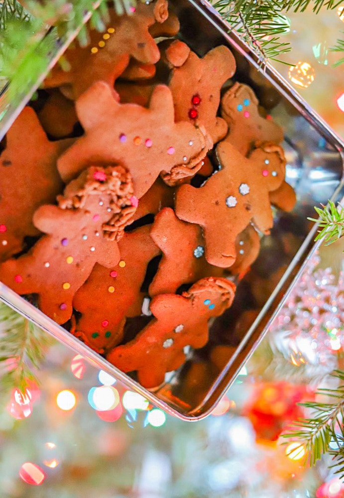 gingerbread men cookies in a tin in front of a christmas tree