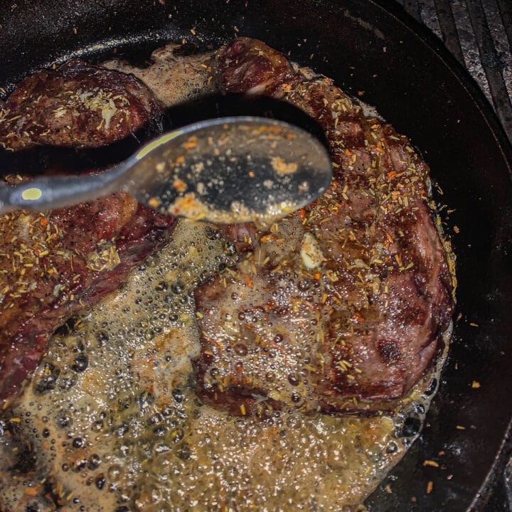 Grilled Ribeyes being basted in a pan