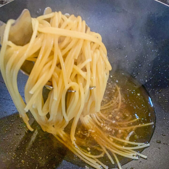 adding spaghetti to a pan
