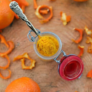 orange powder in a jar with oranges around it