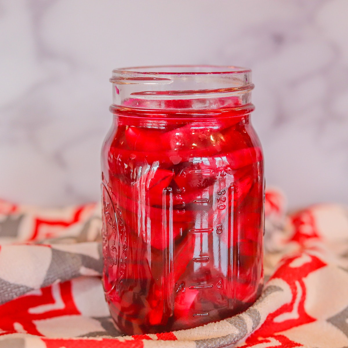 Bottles with homemade red juice and jars of various pickled