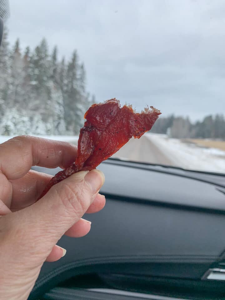 a piece of dehydrated meat being held up infront of a car window