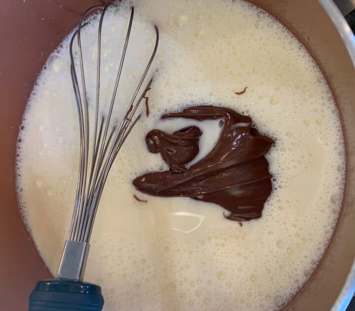Nutella being whisked into a pot of cream 