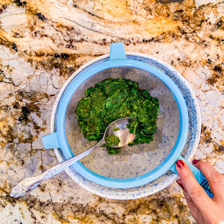 cooked spinach in a strainer over a bowl