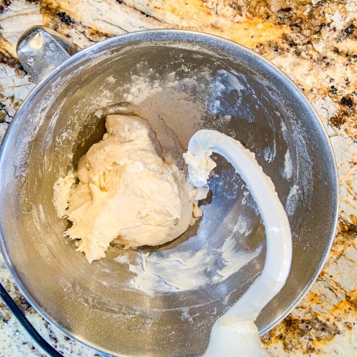 mixer with hook attachment over a bowl of dough