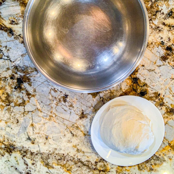 a silver bowl with a dough ball next to it