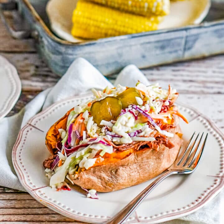 sweet potato topped with pulled pork with corn in the background