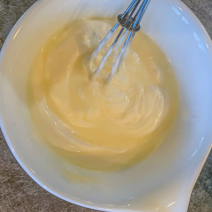 a small white bowl of sour cream with a small whisk 