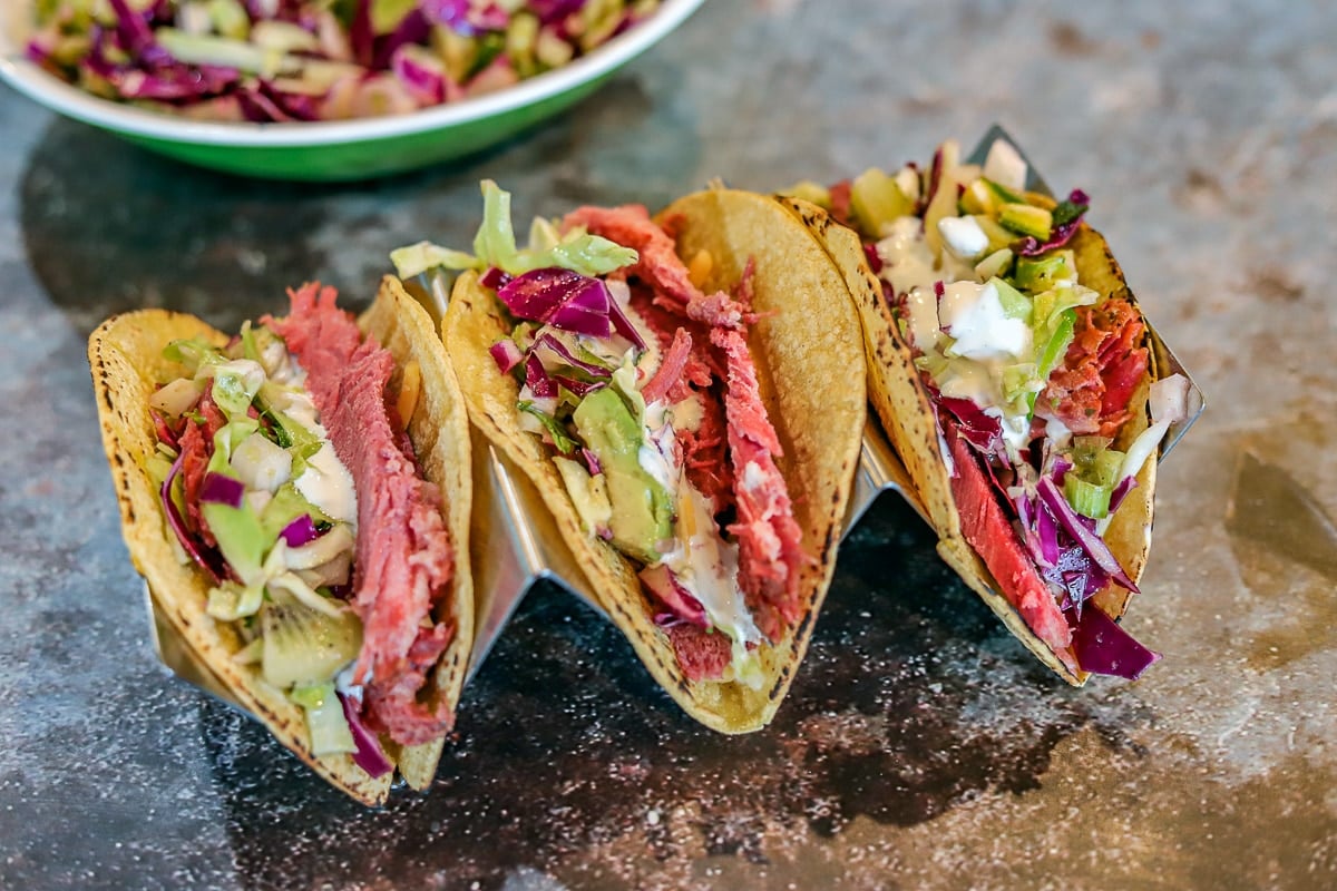 3 corned beef Irish tacos on a taco holder with slaw in the background