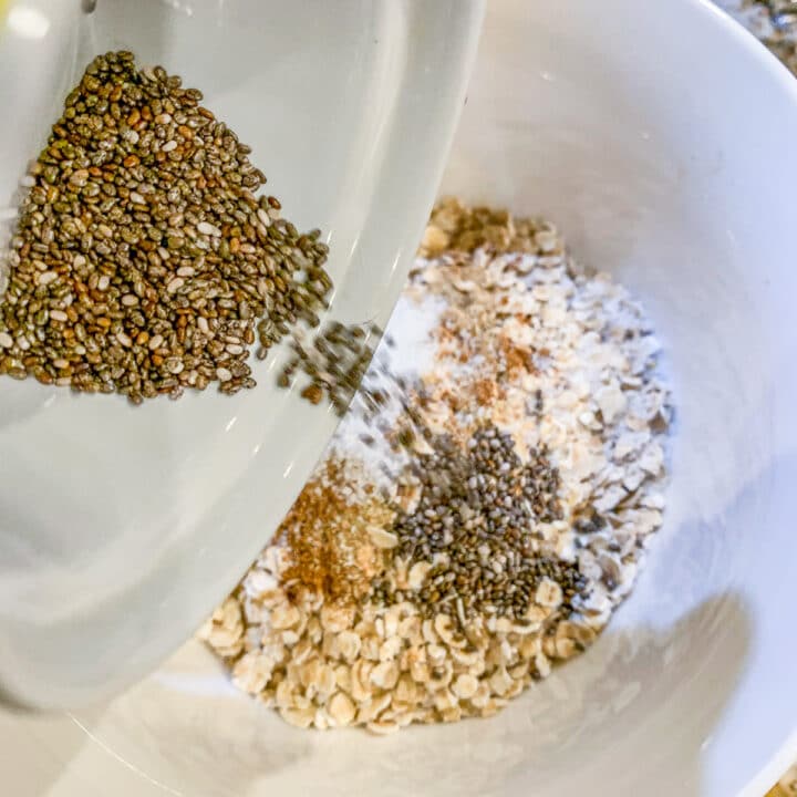 adding chia seeds to a bowl of Mediterranean overnight oats
