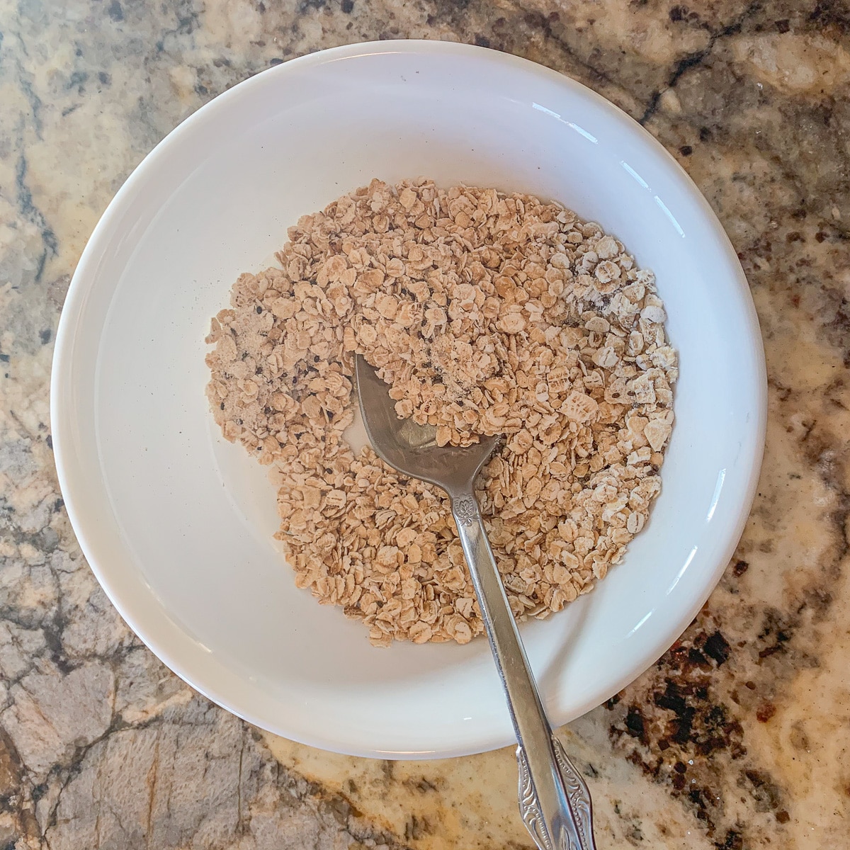 white bowl with dry oats and a spoon