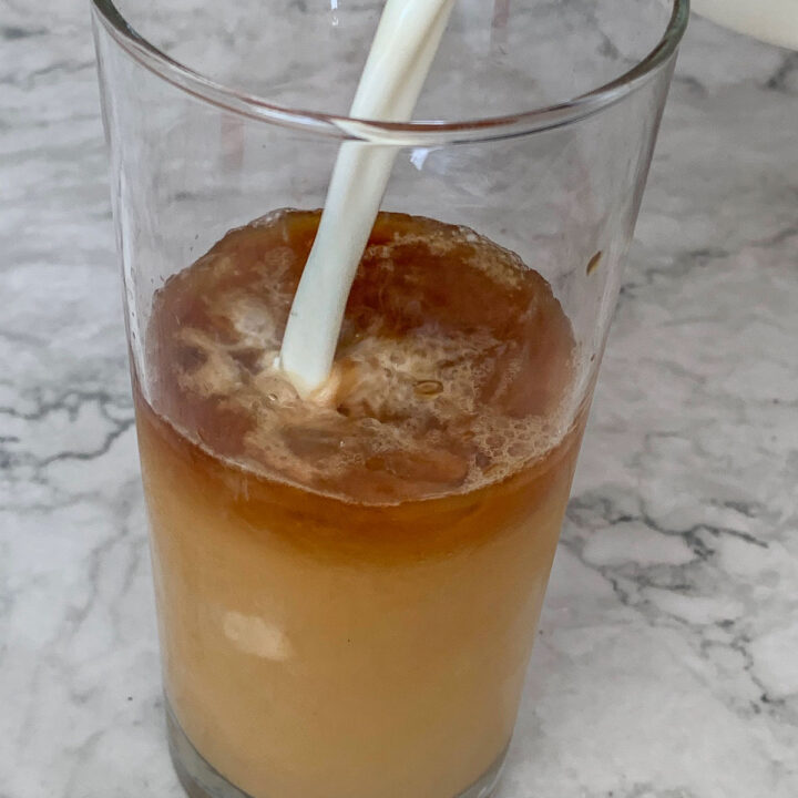 adding milk to an iced latte