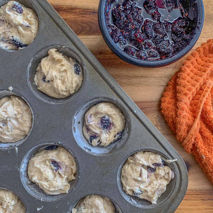 uncooked mulberry muffins in a tin with mulberry jam on the side