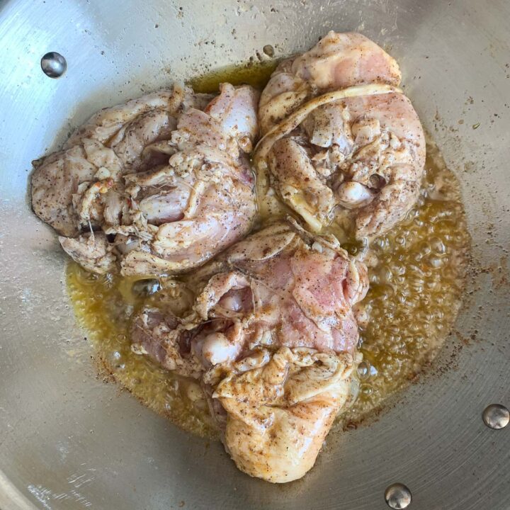 3 pieces of chicken cooking in a pan