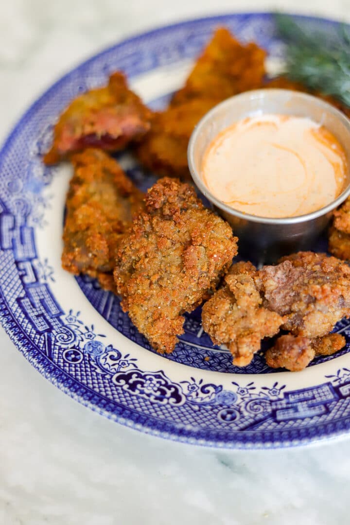 fried nuggets on a blue and white plate with dipping sauce