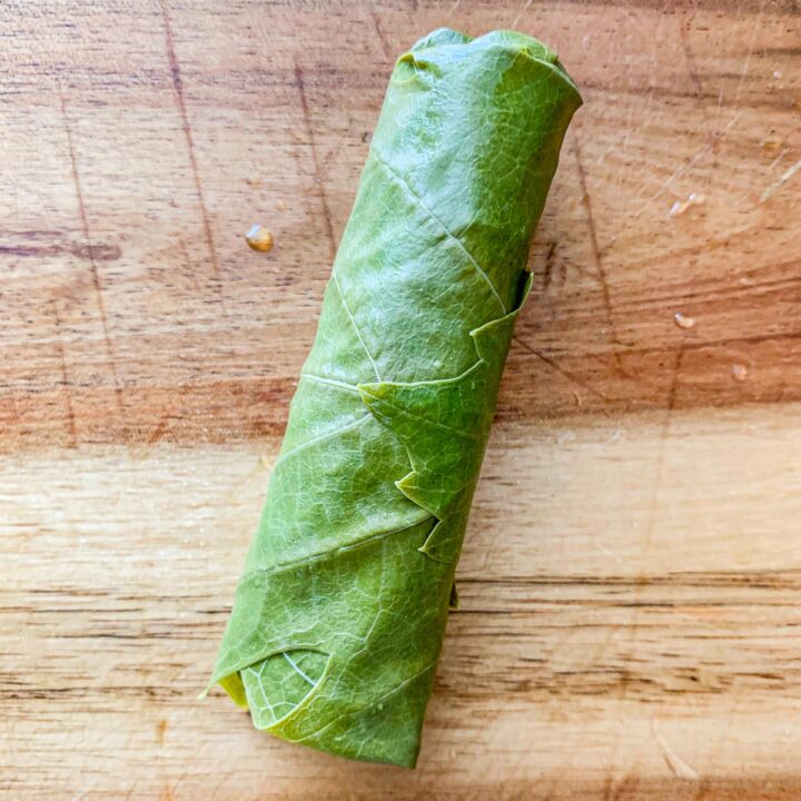 1 grape leaf dolma, uncooked on a cutting board