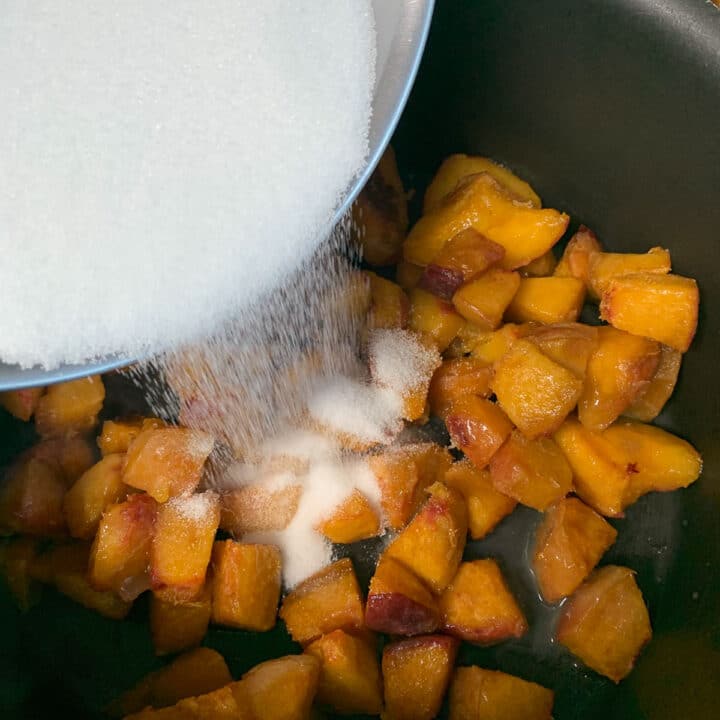 adding sugar over chopped peaches
