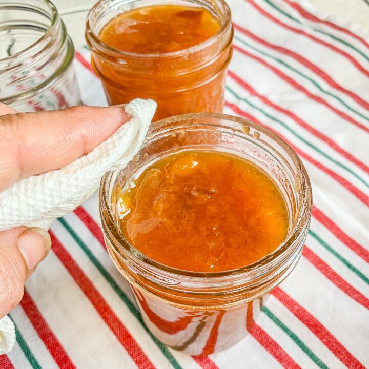 wiping the rim of peach preserves being canned