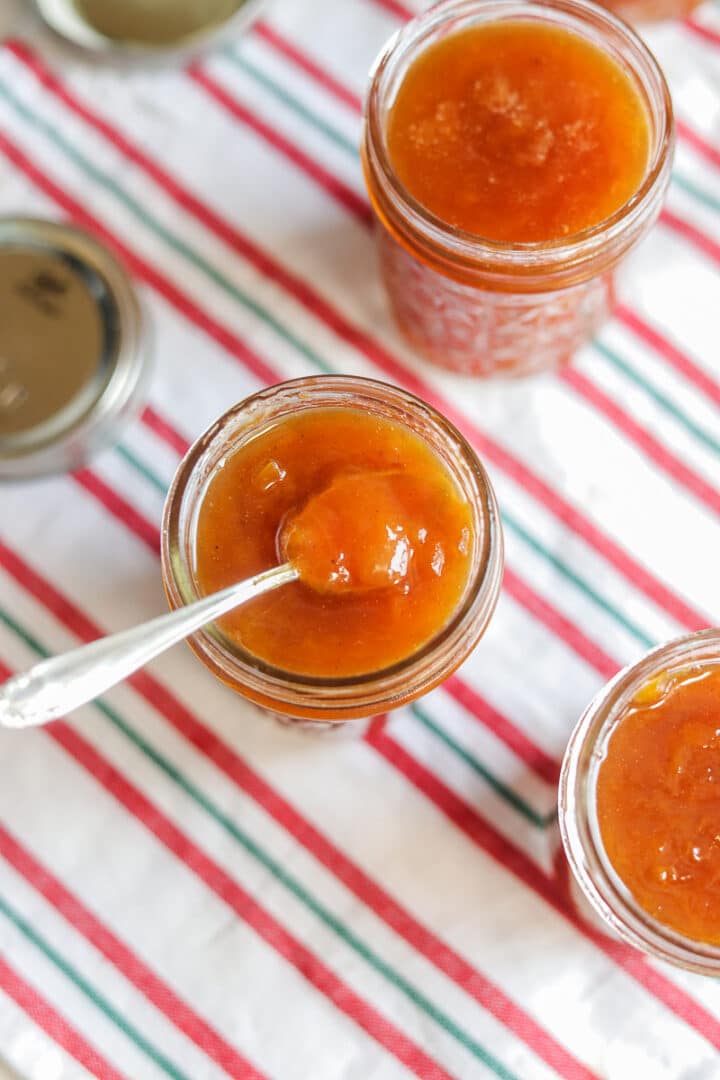 peach preserves in 3 jars over a striped towel 