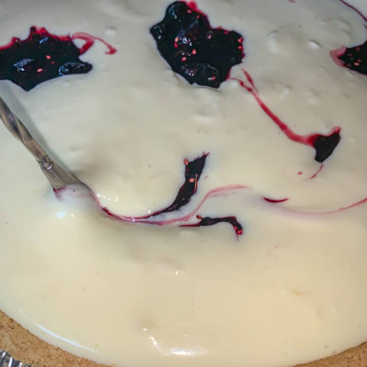 mulberry topping being swirled into cheesecake