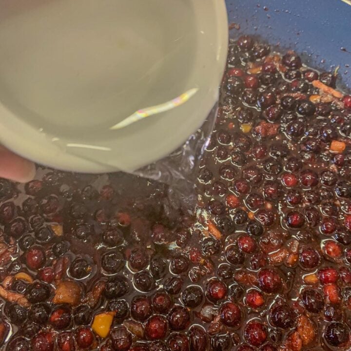 pouring water over berries in a pan