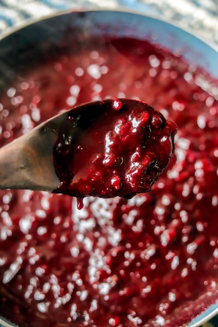 huckleberry chutney in a pan with a spoon full over the pan
