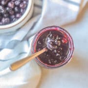 huckleberry jam in a jar with huckleberries on the side
