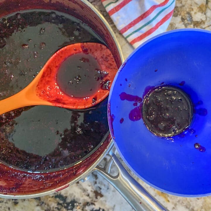 spooning huckleberry jam into jars