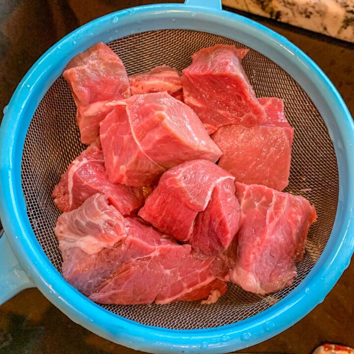 cubed meat in a strainer