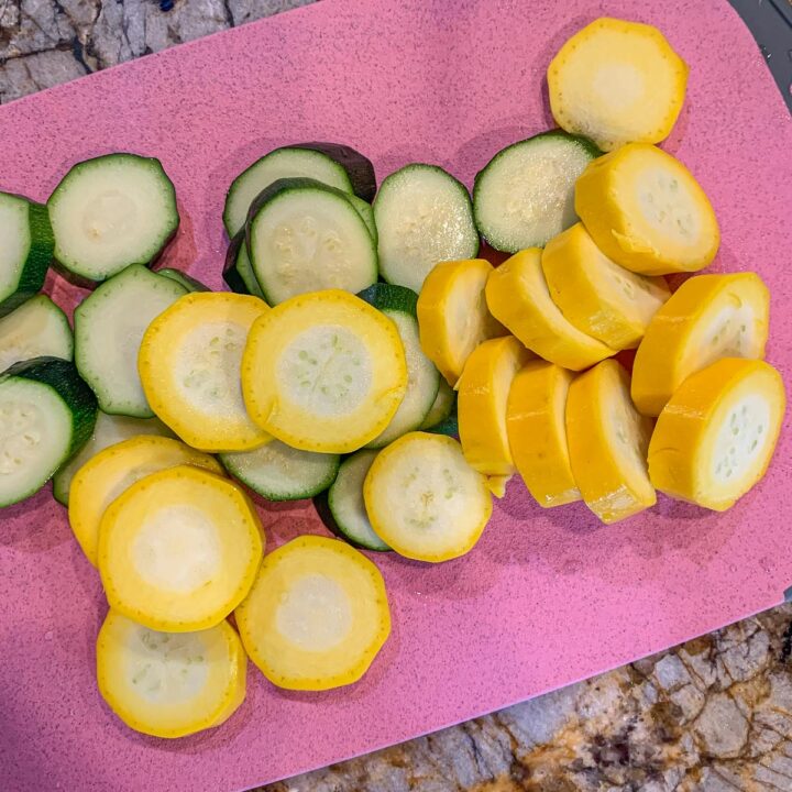 sliced green and yellow zucchini on a pink cutting board