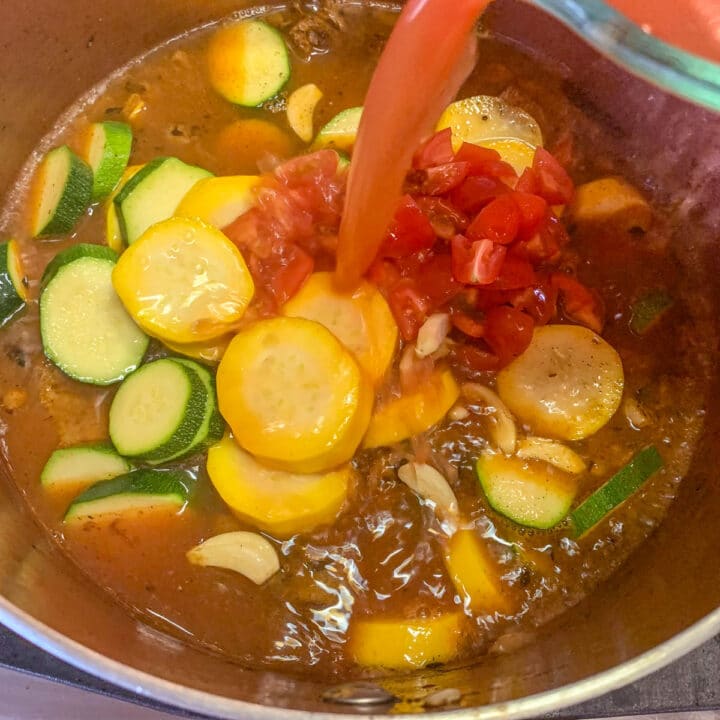 pouring tomato sauce over zucchini stew