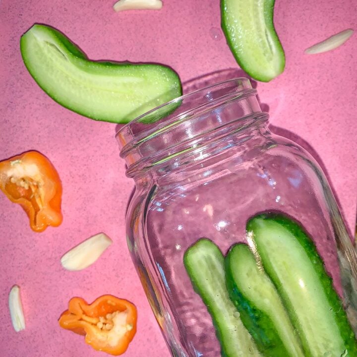 a mason jar on its side, with sliced cucumbers in it and around it