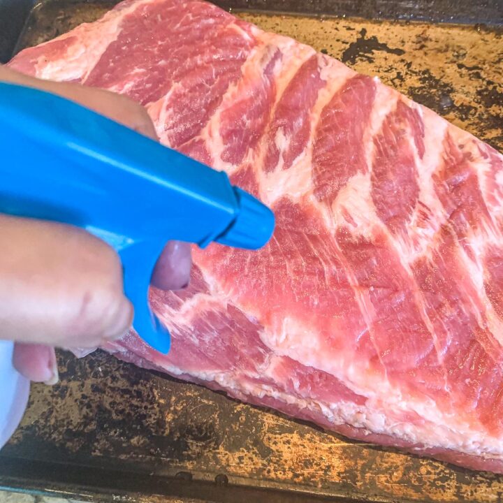 spraying uncooked ribs with apple juice