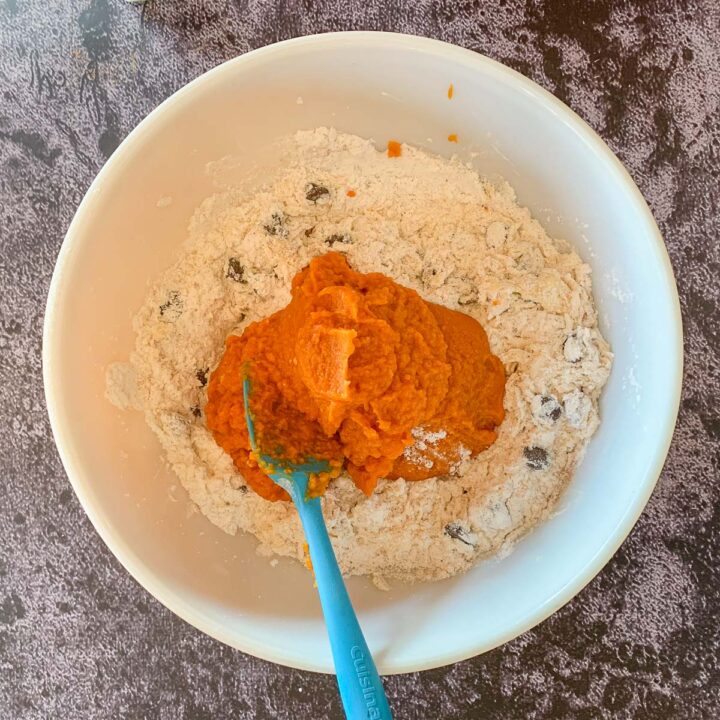 adding pumpkin mix to a bowl of flour