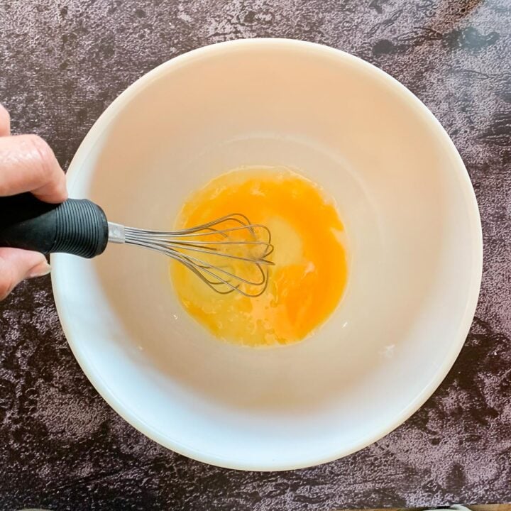 whisking eggs in a white bowl