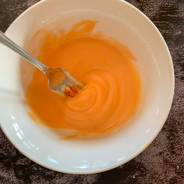 pumpkin colored frosting in a white bowl