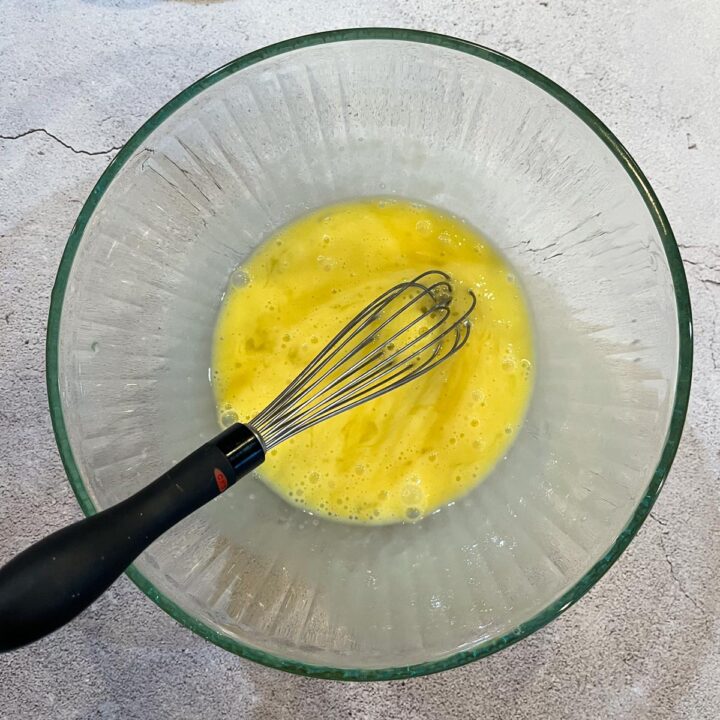 eggs being whisked in a glass bowl