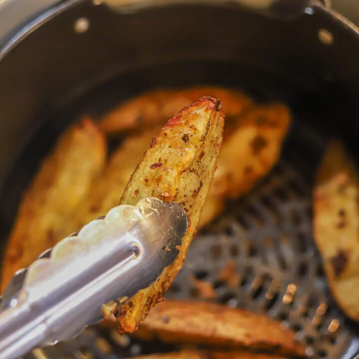 flipping air fryer potato wedges with tongs