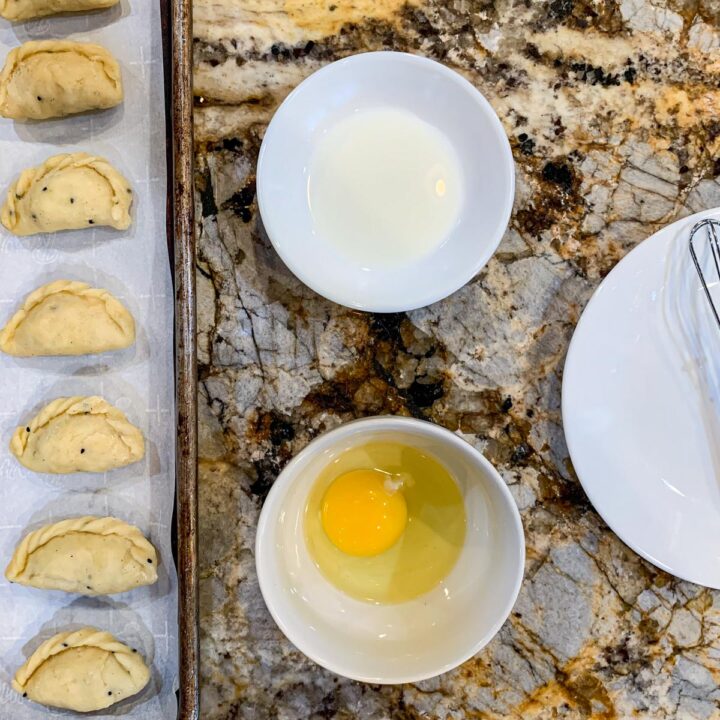 a bowl with an egg, another with milk, and cookies on a tray on the side