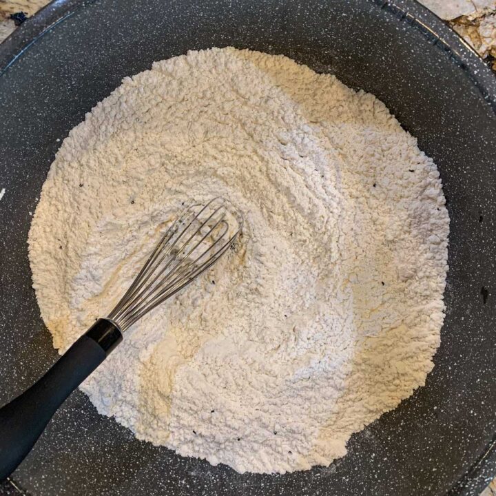 a bowl of flour with a whisk in the middle
