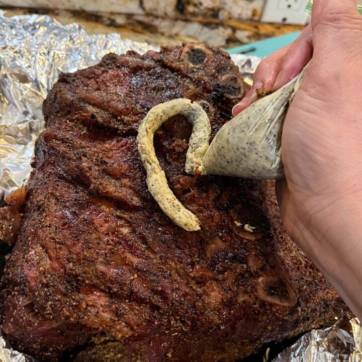 adding herbed butter to smoked prime rib