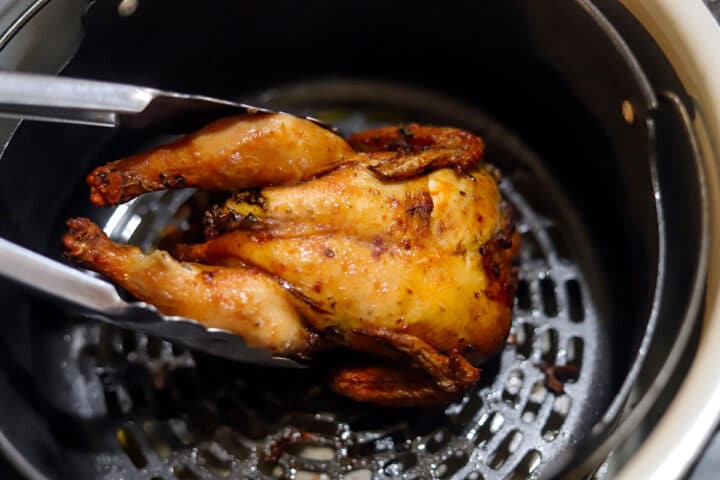 air fryer Cornish hen being removed with tongs