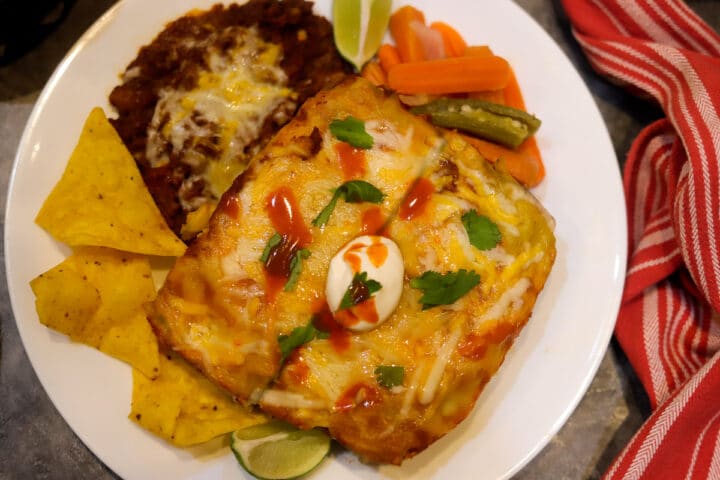 green enchilada with beans, salsa, and chips