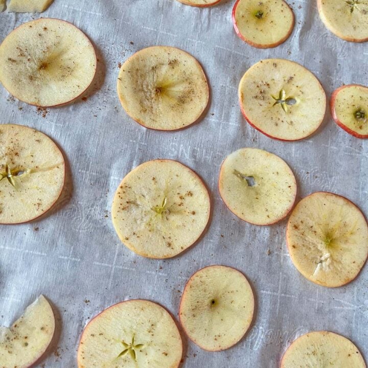 apple slices on parchment paper sprinkled with cinnamon
