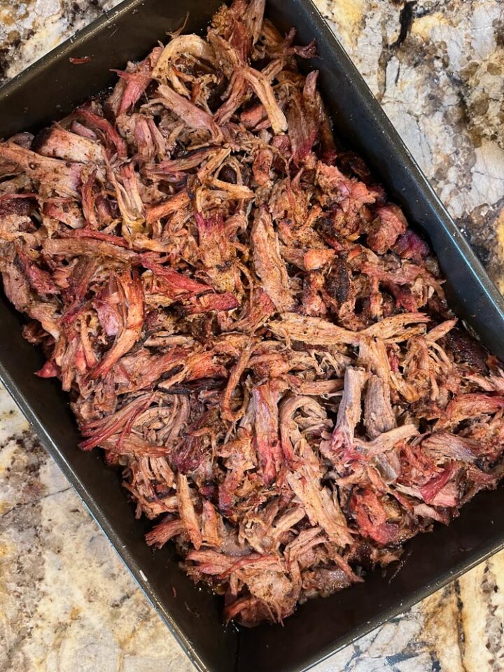 Traeger pulled pork in a metal pan on the grill