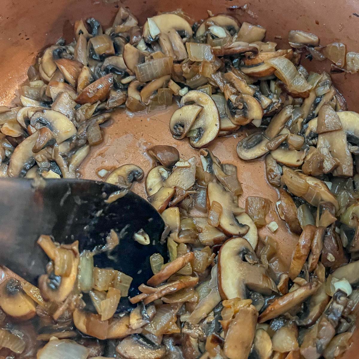stirring mushrooms in a pot