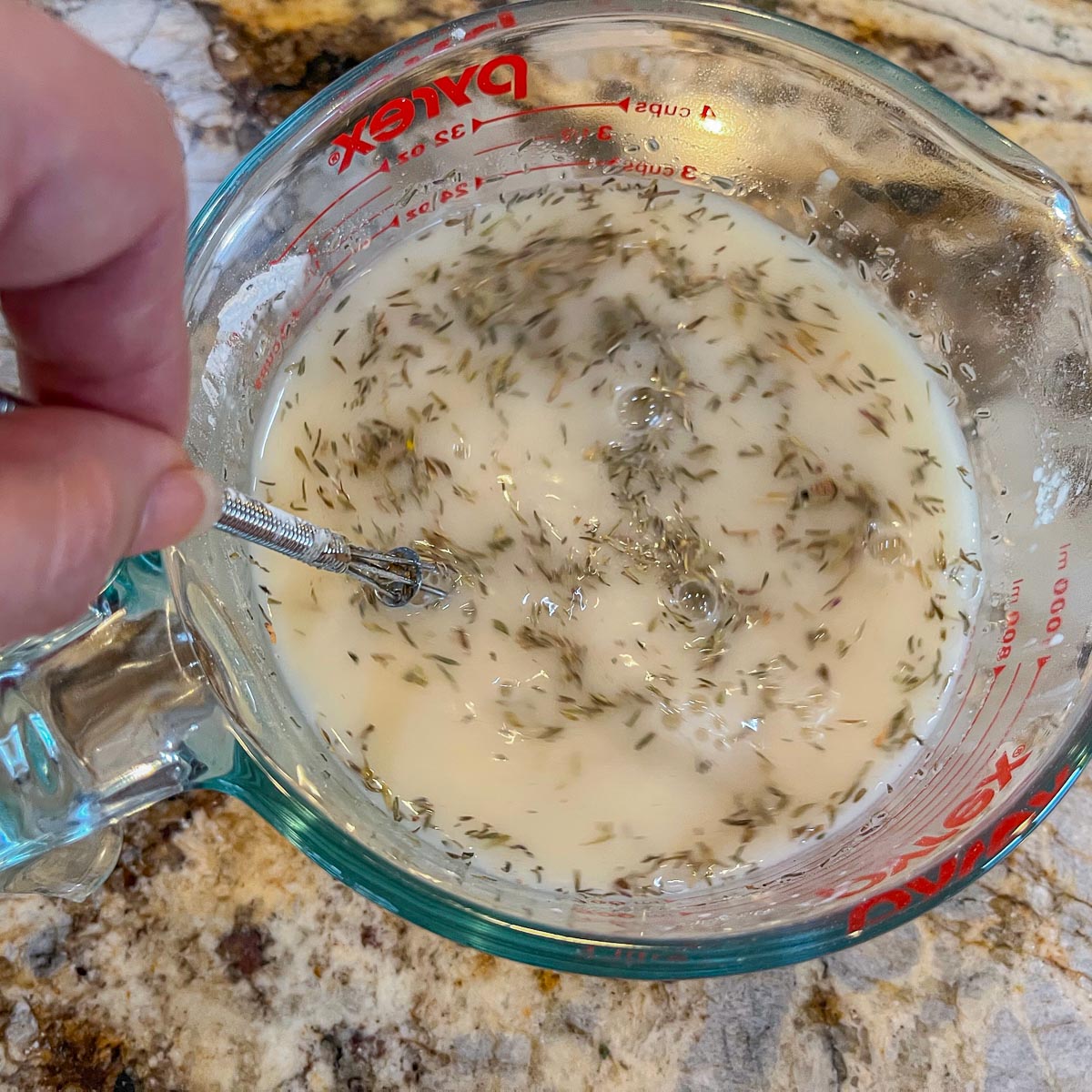 broth and herbs in a measuring cup