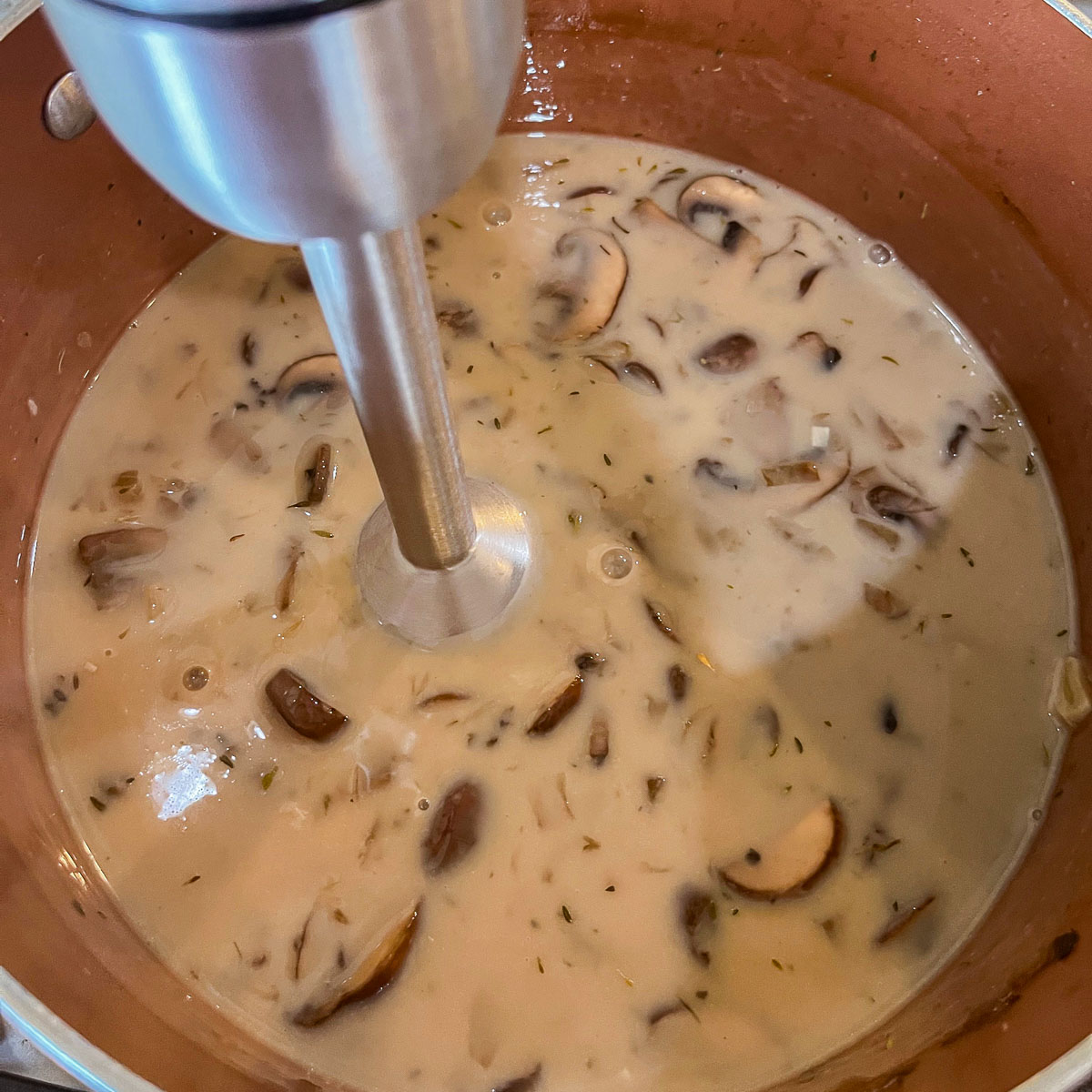 blending vegan mushroom soup with immersion blender