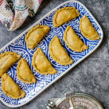 uncooked empanadas on a blue and white tray
