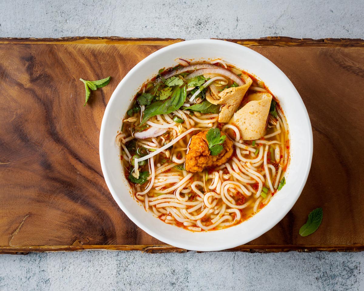 ramen in a white bowl over a wooden plank